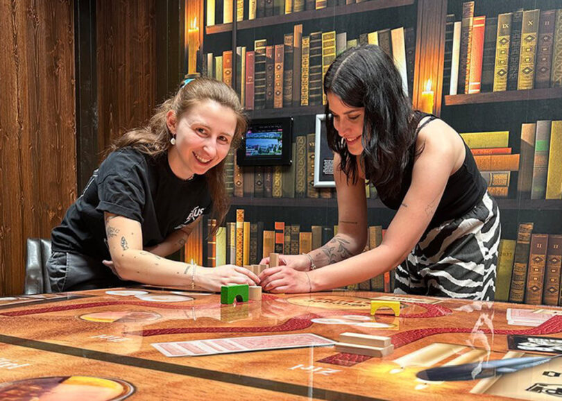 Zwei Personen bauen aus Holzklötzen Dominoreihe