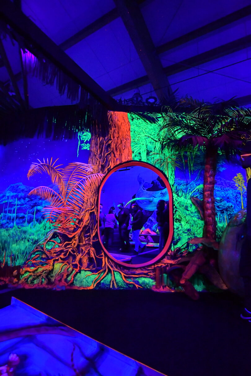 Freunde spielen auf einer leuchtenden Neongolf-Bahn